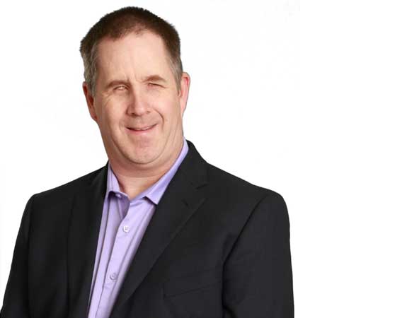 Tim Black of Blind Like Me is seen wearing a suit jacket and smiling.