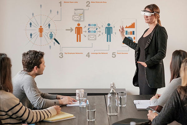 Yvonne Felix, CNIB, wearing eSight's low vision aid while presenting at the front of a boardroom meeting
