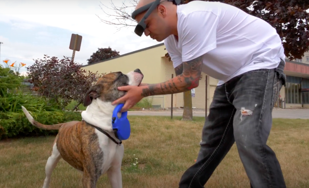 eSight user, Anthony playing with his dog while wearing his eSight 4.