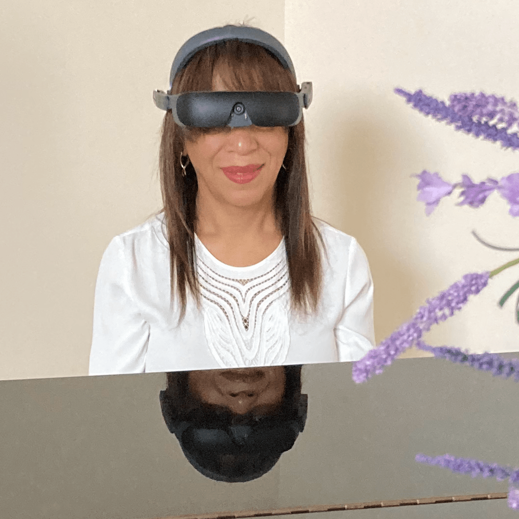 eSight user Jeanette sitting behind her piano while wearing her eSight 4.
