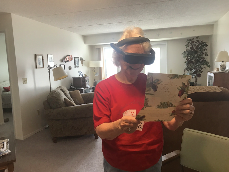 eSight user, Velma Baudette smiles as she reads an old holiday card with the help of her eSight 4 device.