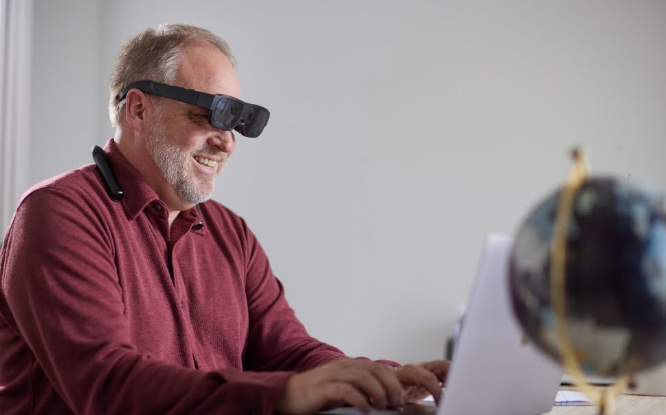 Man using computer with eSight goggles